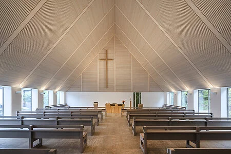Innenansicht der Evangelischen Kreuzkirche Bad Abbach mit direktem Blick auf das große Kreuz an der Stirnseite und den sich darunter befindlichen Altar