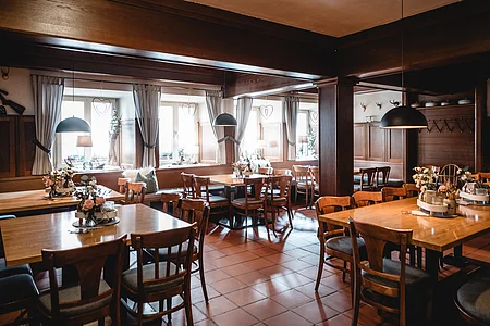 Ein traditionelles Restaurant mit Holzmöbeln, mehreren Tischen und Stühlen, dekoriert mit Blumenarrangements.