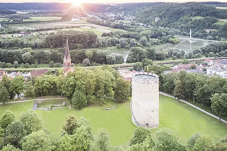 Bad Abbach Burgberg Vogelperspektive Luftaufnahme einer Landschaft mit einem runden Turm und einer Kirche mit spitzem Turm, umgeben von Bäumen und Wiesen.