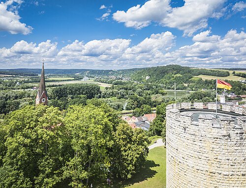 Blick vom Burgberg Luftbild vom Heinrichsturm mit dem grünen Donautal im Hintergrund. Der Himmel ist blau-weiß.
