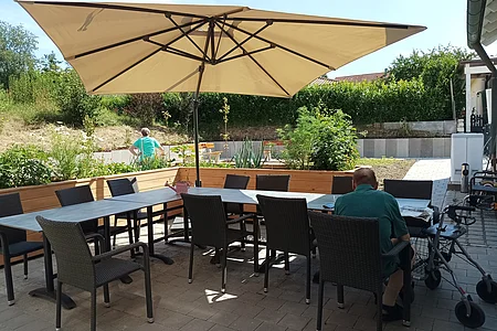Bestuhlte Terrasse mit zwei Hochbeeten und im Hintergrund der Garten.