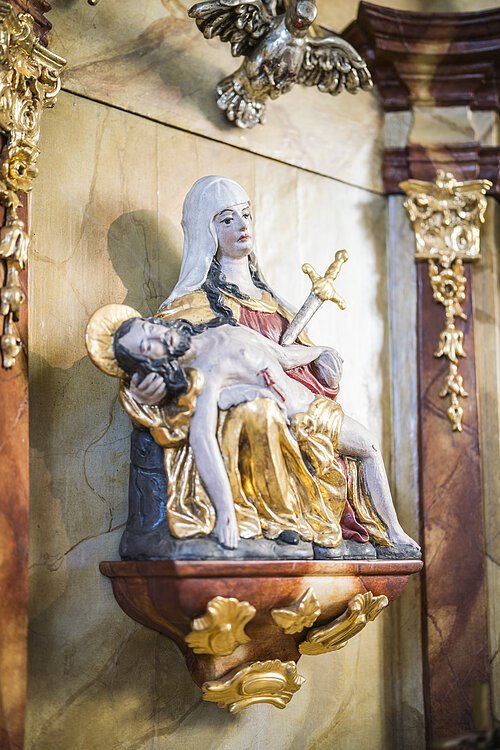 Frauenbründl Innen Skulptur einer sitzenden Frau mit Heiligenschein, die einen liegenden Mann auf ihrem Schoß hält.