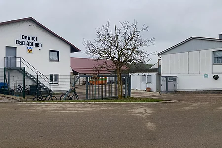 Gebäude mit Aufschrift „Bauhof Bad Abbach“, Zaun, Baum ohne Blätter und grauer Himmel im Hintergrund.