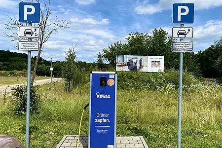 Ladesäule für Elektroautos mit zwei Parkschildern und Hinweis auf Abschleppgefahr bei Falschparken.