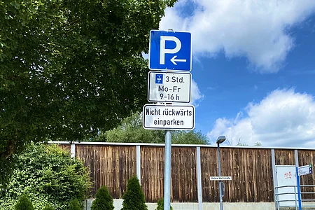 Parkplatzschild mit Pfeil nach links, zeitliche Begrenzung Mo-Fr 9-16 Uhr, 3 Stunden Parkdauer, kein rückwärts Einparken.