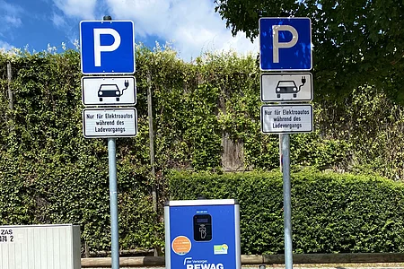 Ladesäule für Elektroautos mit Parkschildern und Hinweis nur während des Ladevorgangs parken.