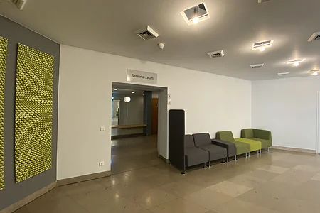 Flur mit Sitzbank und Eingang zu einem Raum mit Schild „Seminarraum“ an der Wand