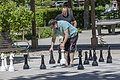 Zwei Männer spielen im Freien Schach mit übergroßen Figuren auf einem Spielfeld aus Steinplatten.