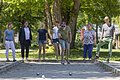Sieben Personen spielen Boule auf einem Sandplatz im Freien, umgeben von Bäumen und Grünflächen.