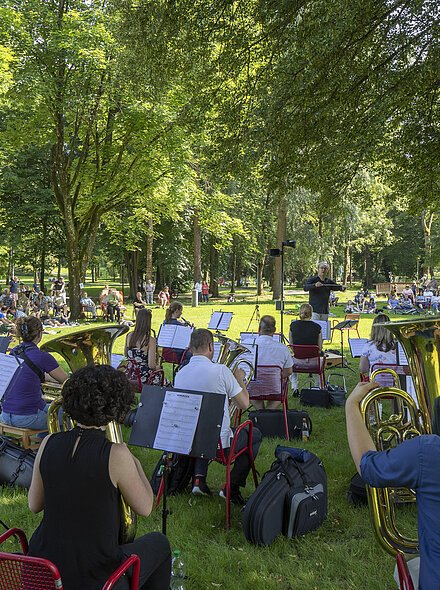 Markt Bad Abbach Kurpark Öffentliche Probe mit Gästen Symphonisches Blasorchester Regensburg Orchester spielt im Park auf Wiese, Publikum sitzt auf Stühlen und Decken unter Bäumen.