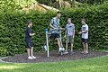 Vier Jungen im Freien, einer nutzt ein Fitnessgerät, die anderen schauen zu und klatschen.