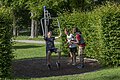 Drei Jungen im Park, einer sitzt auf einer Schaukel, zwei stehen daneben und schauen zu.