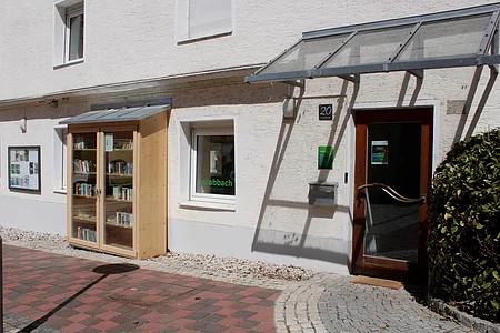 Außenansicht eines Hauses mit Bücherregal im Freien, Tür mit Glas und Hausnummer 20.