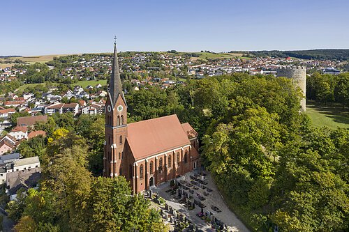 Kirche St. Nikolaus in Bad Abbach Luftaufnahme einer Kirche mit Friedhof, umgeben von Bäumen und Wohnhäusern in einer ländlichen Gegend.