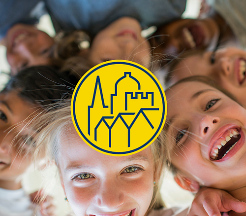 Gruppe lachender Kinder, die in einem Kreis von oben in die Kamera schauen, mit einem gelben Logo mit Gebäudesilhouetten in der Bildmitte.