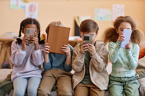 Group of young children holding smartphones and hiding faces Group of young children holding smartphones and hiding faces, gen Alpha
